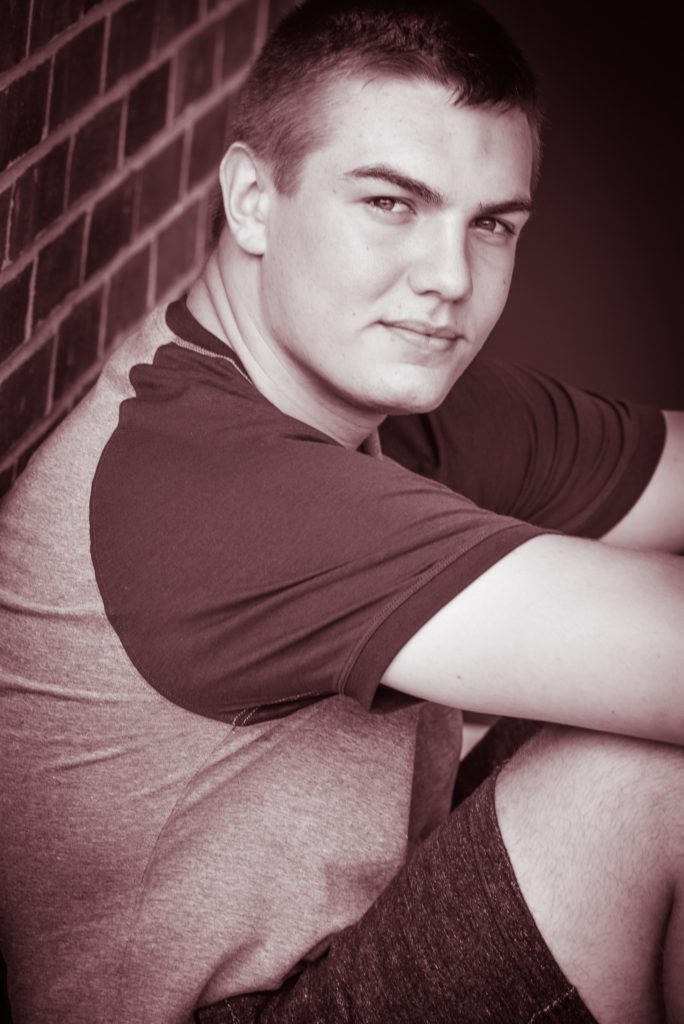 A man sitting on top of a chair in front of a brick wall.